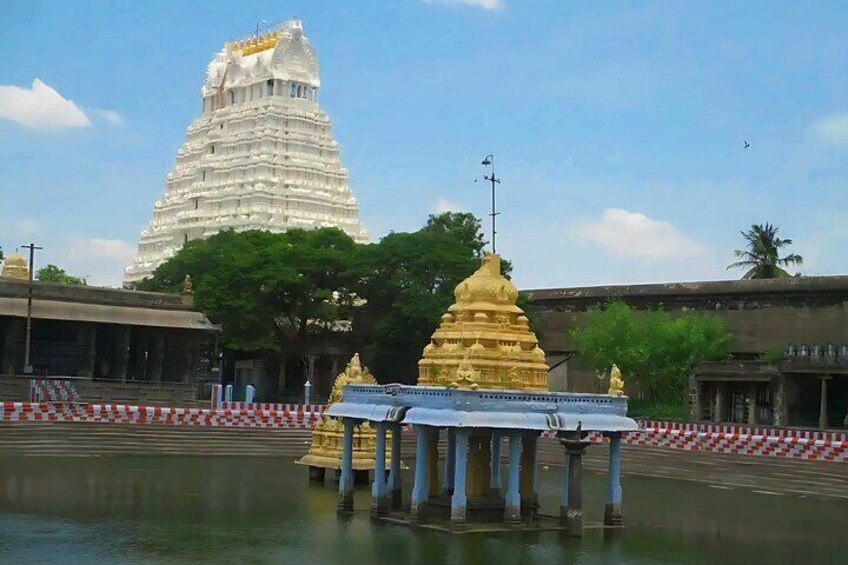 A temple complex with a large white tower and golden spires. 1