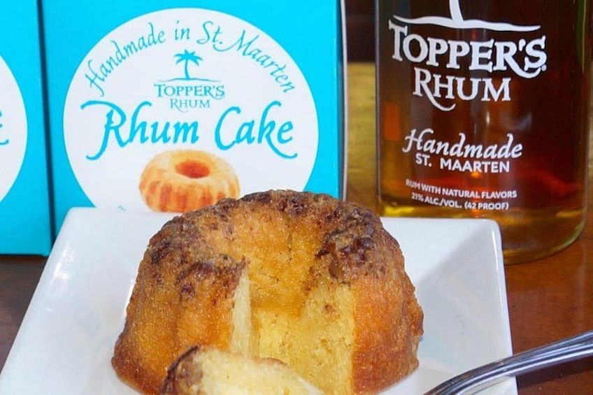 A rum cake with a label reading 'Handmade in St. Maarten' and a bottle of Topper's Rum. 3