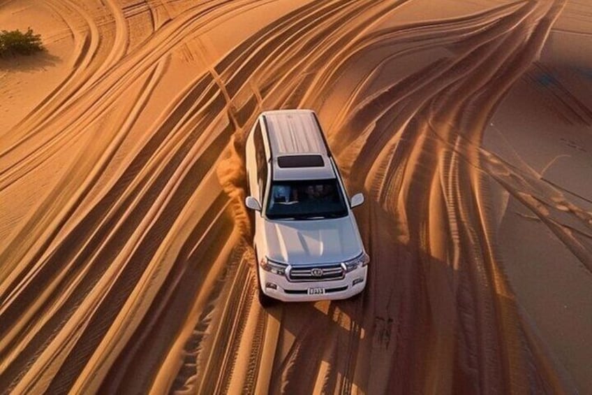 A white SUV driving on a sandy road in a desert. 1
