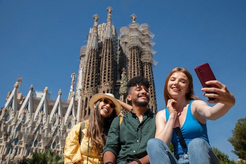 Drie mensen maken een selfie, met de Sagrada Familia op de achtergrond. 4