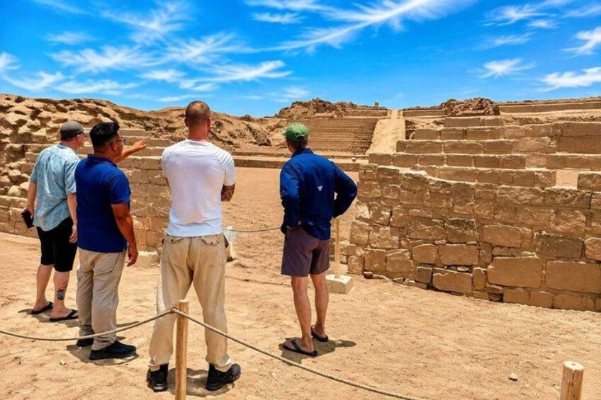 A group of people standing at the base of ancient stone structures. 1