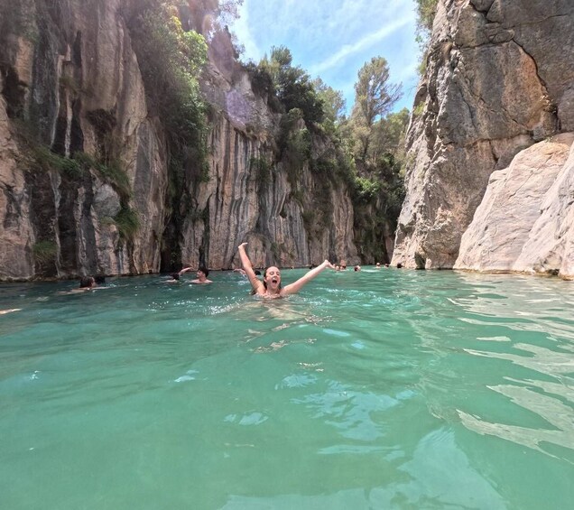 A swimmer in a natural pool surrounded by rocky cliffs. 3