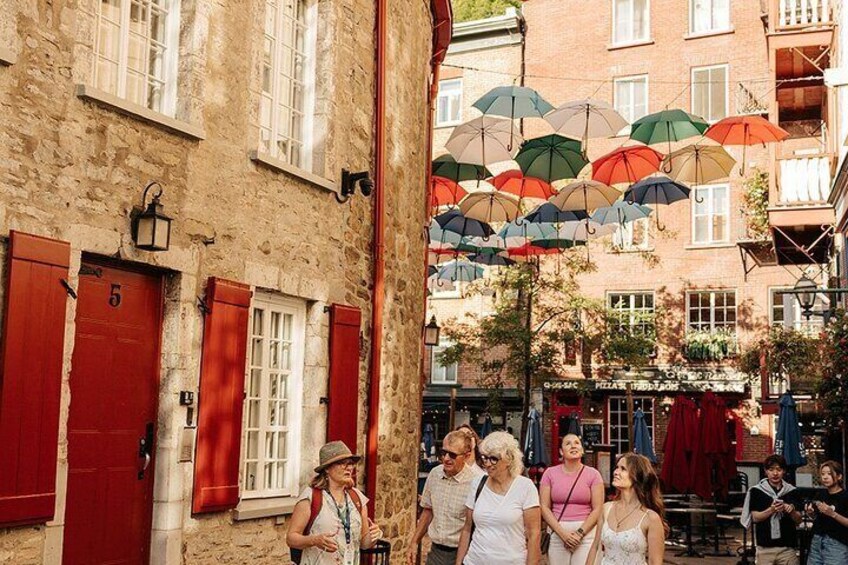 Een straat met rode luiken, een gebouw met een bord en kleurrijke parasols. 1