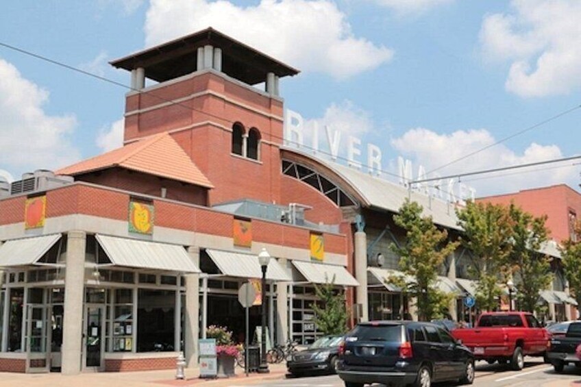 A building with a sign that reads 'RIVER MARKET.' There are cars parked in front, and a red truck is visible. 2