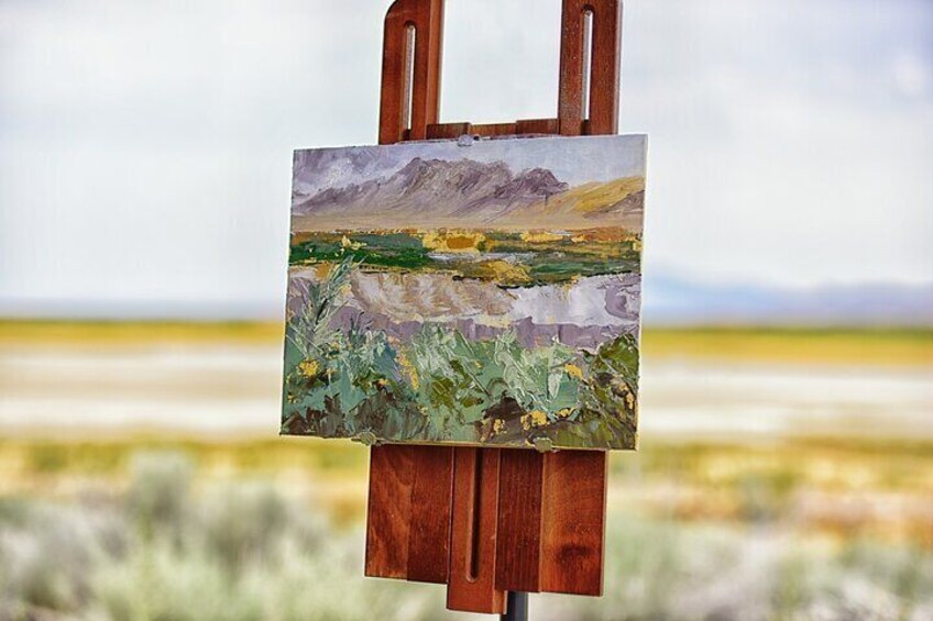 Un caballete con una pintura de paisaje de montañas y flores. 5