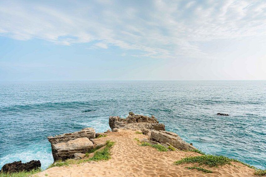 Un paisaje costero con una playa arenosa, afloramientos rocosos y el océano. 5
