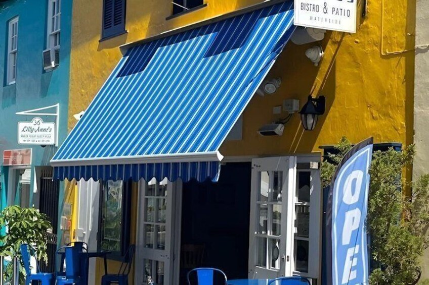 A colorful building with a blue awning, a sign for 'BISTRO & PATIO,' and a 'OPEN' sign. 3