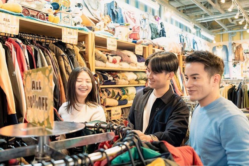 A clothing store with racks of clothes and a sign indicating a sale. 3
