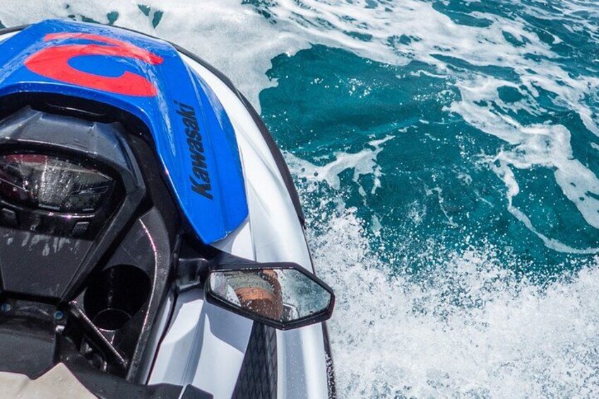 Een vaartuig met een blauw en rood Kawasaki-logo, een witte romp en een kiel achter zich. 3