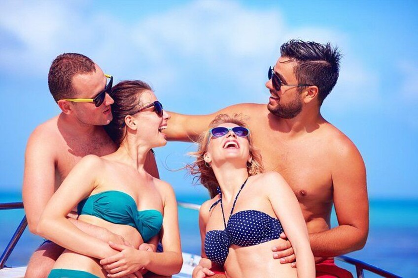 A group of people on a boat with a clear blue sky and ocean in the background. 4