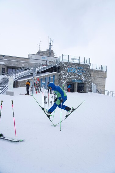 A person skiing on a snowy slope with a building in the background. 3