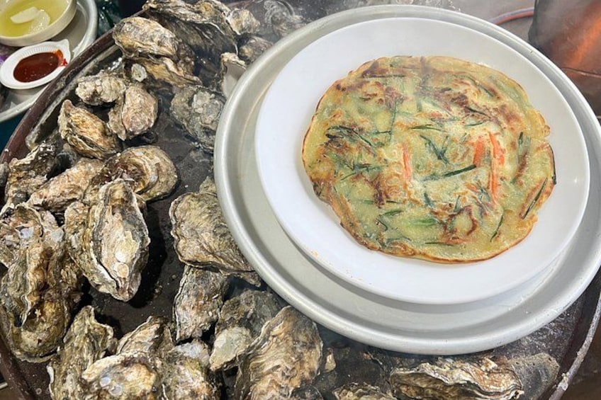 A plate of food with a pancake and a tray of oysters. 2