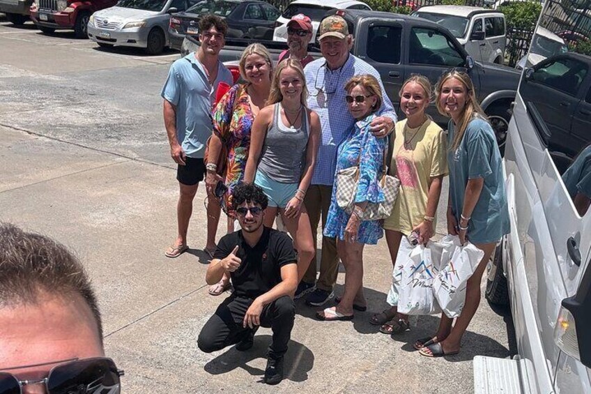 A group of people standing on a concrete surface with cars parked in the background. 5