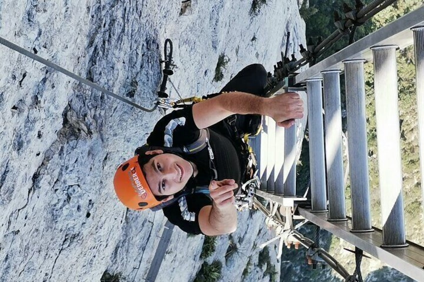 Eine Person seilt sich einen steilen, felsigen Abhang hinab, gesichert mit Klettergurt und Helm. 4