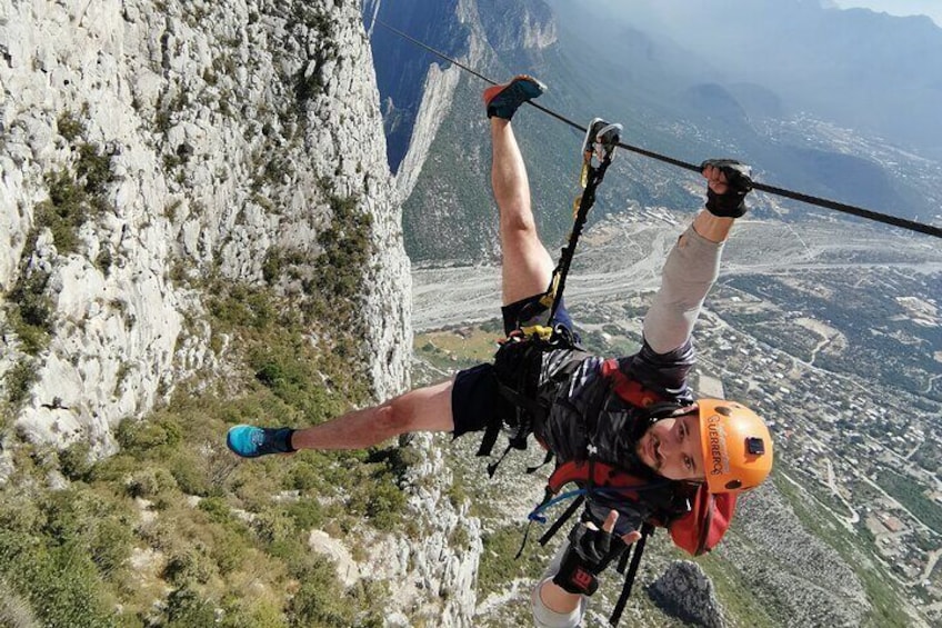 Eine Person seilt sich an einer felsigen Klippe ab, im Hintergrund ist eine Stadtlandschaft zu sehen. 2