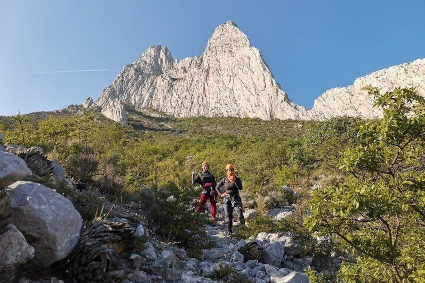 Zwei Wanderer auf einem felsigen Pfad, im Hintergrund ein Berg. 3