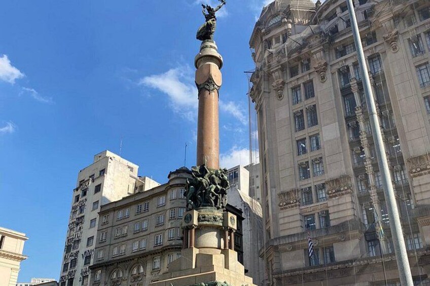 A tall monument with a statue on top, surrounded by buildings. 5