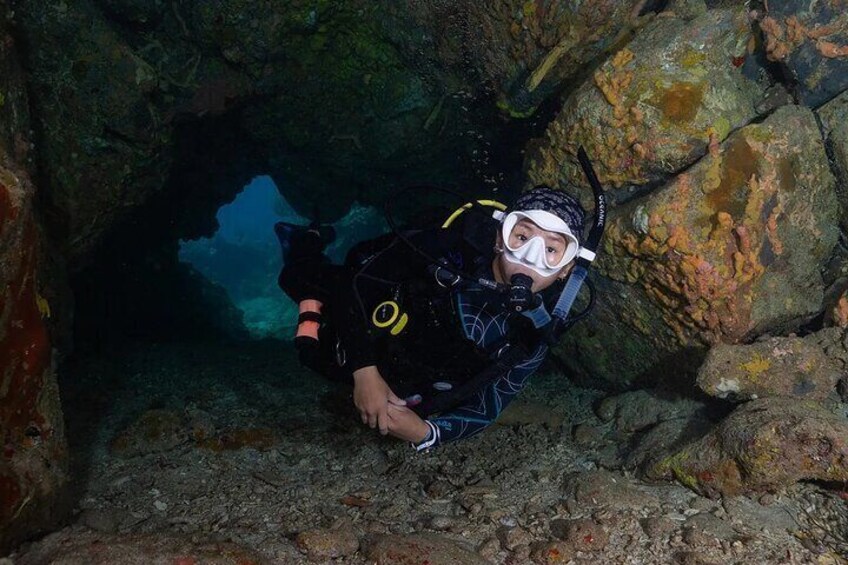 A diver in a cave with rocky walls and a visible opening. 2