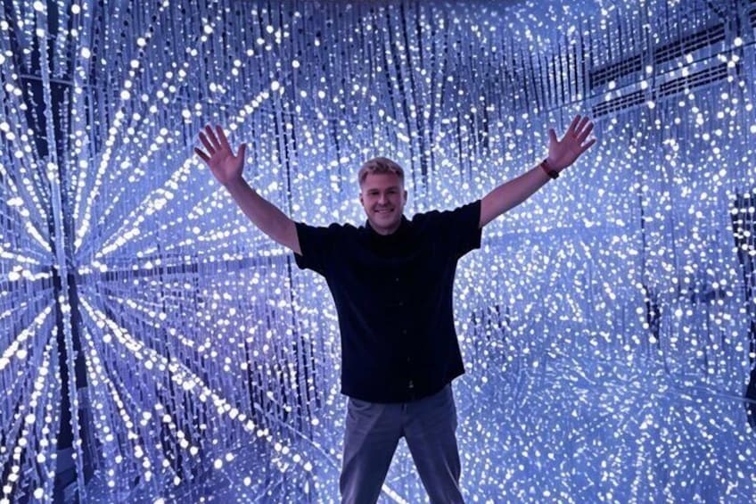 A person standing in front of a light installation with arms outstretched. 4