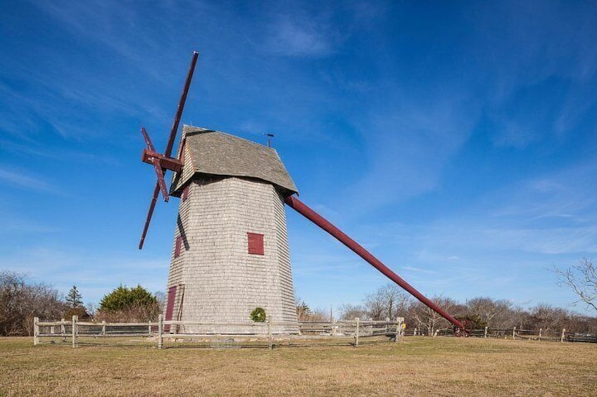 Un molino de viento con una paleta roja y un cuerpo blanco, sobre un cielo azul despejado. 3