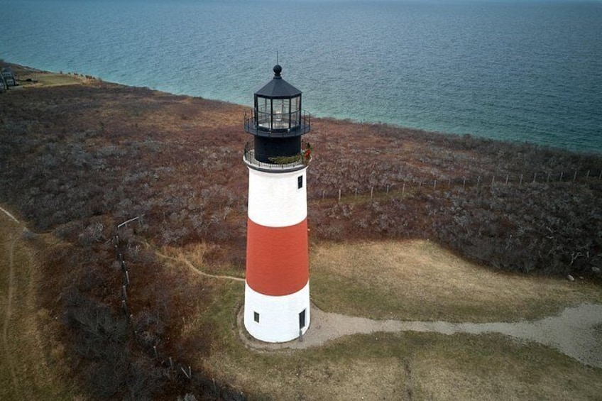 Un faro rojo y blanco sobre una colina cubierta de hierba, con vistas al mar. 2