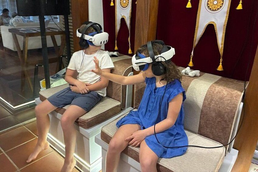 Two children sitting on a couch wearing VR headsets. 2