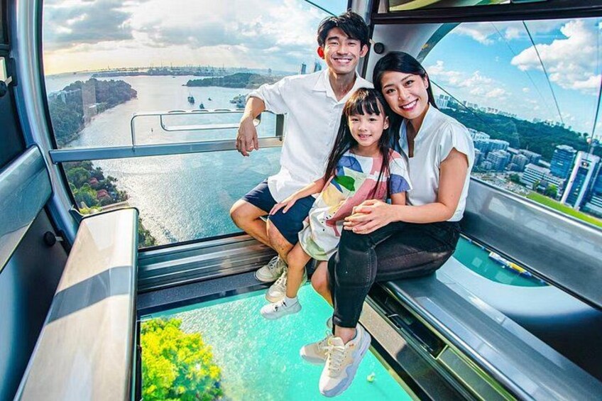 A family on a glass-bottomed boat with a cityscape and river in the background. 3