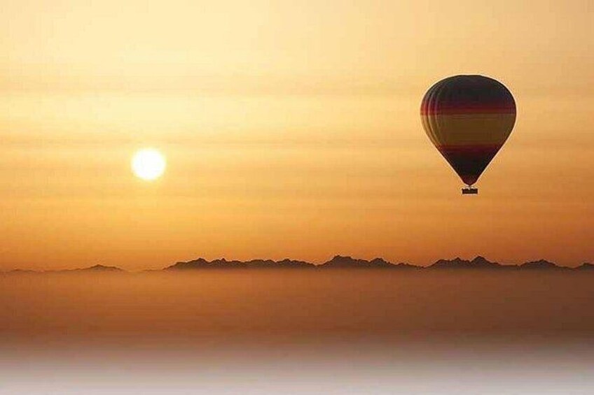 A hot air balloon flying during sunset with mountains in the background. 3