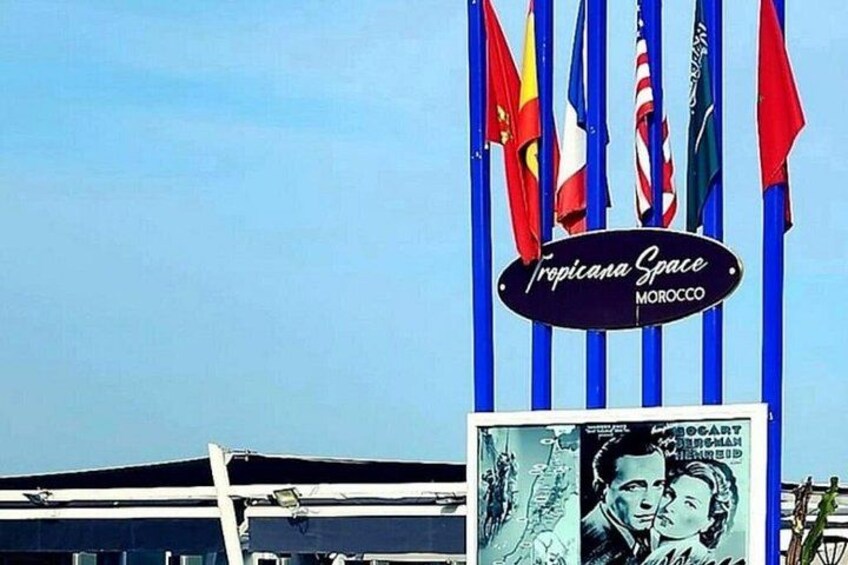 A Tropicana Space sign with multiple flags, including the American flag, and a poster with a man's face. 4