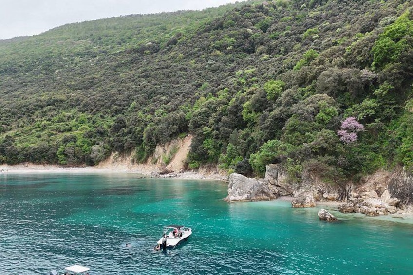 A boat on turquoise water, rocky coastline, and dense green hills. 5