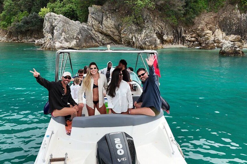 A group of people on a boat with clear turquoise water and rocky cliffs in the background. 2