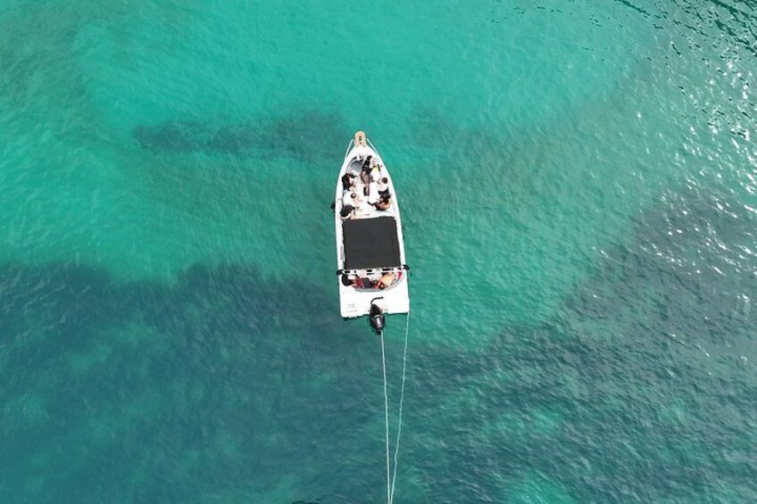 A small boat anchored in clear turquoise water. 4