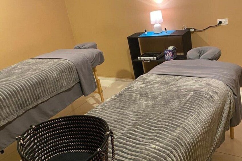 A room with two beds, a bedside table with a lamp, and a black woven basket. 3
