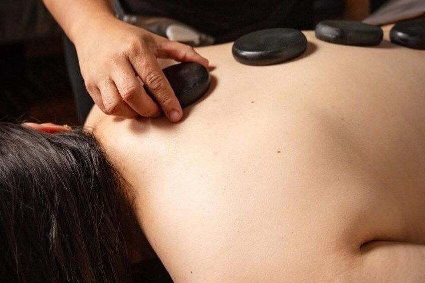 A person receiving a back massage with black stones. 4