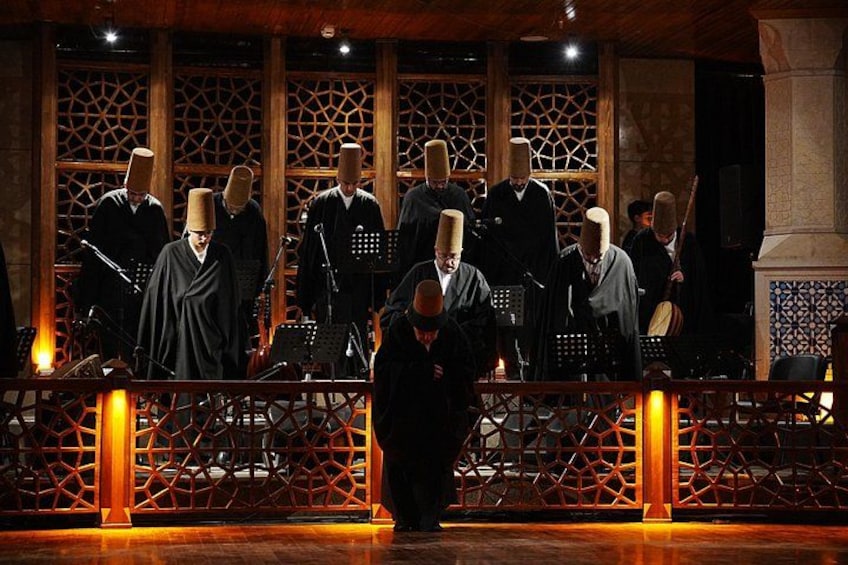 A group of musicians in traditional attire performing on a stage with a geometric patterned backdrop. 3