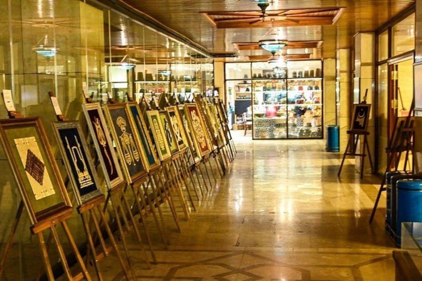 A corridor with framed artworks on easels, a polished floor, and a ceiling fan. 4