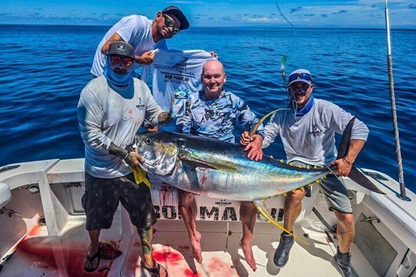 Three people on a boat holding a large fish. 3