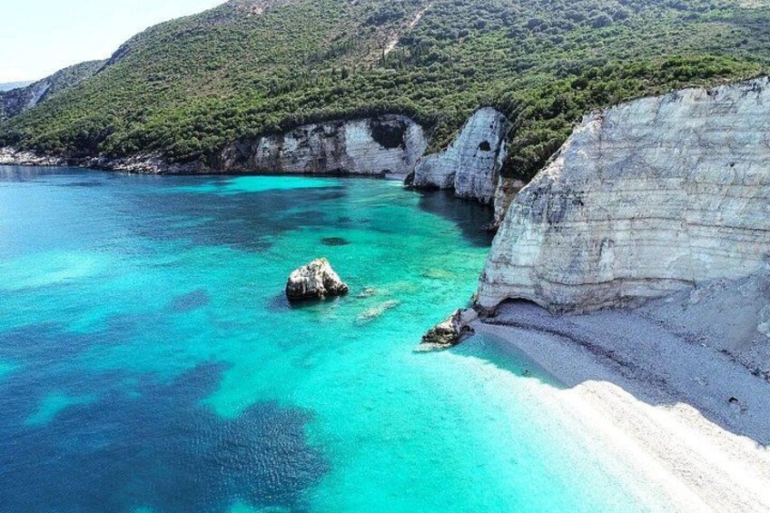 A coastal landscape with clear turquoise waters, white sandy beaches, and rocky cliffs. 1