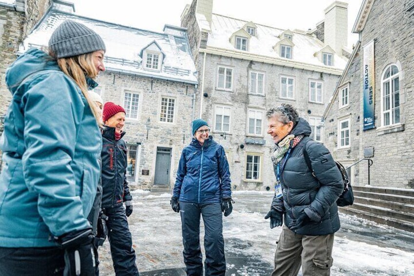 A group of people standing in a snowy courtyard with historic buildings in the background. 5