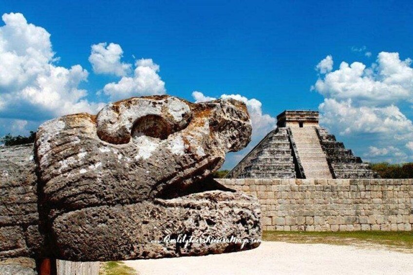 A large stone head sculpture, a pyramid, and a clear blue sky. 5