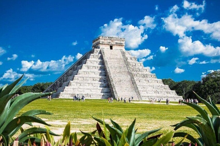 A large pyramid structure with a clear sky and green grass in the foreground. 3