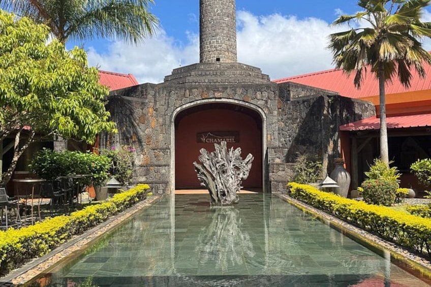 A stone archway with a sign, a reflective pool, and a palm tree. 4