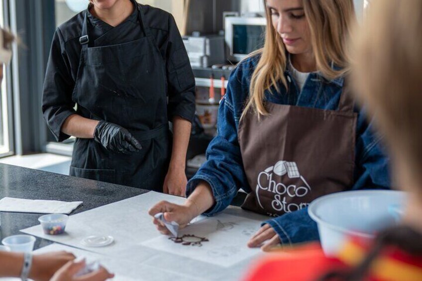 A person wearing a brown apron with a logo, working at a counter with papers and a cup. 5