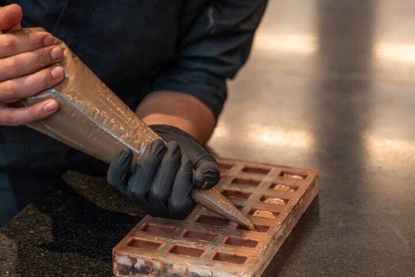 A person pouring a liquid from a bottle into a tray with multiple compartments. 3