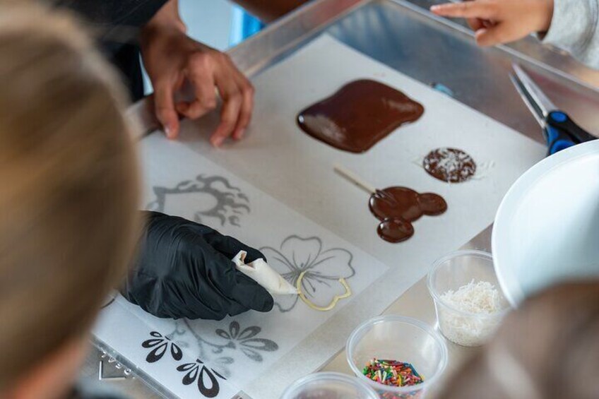 A person using a scraper to spread chocolate on a parchment paper. 2