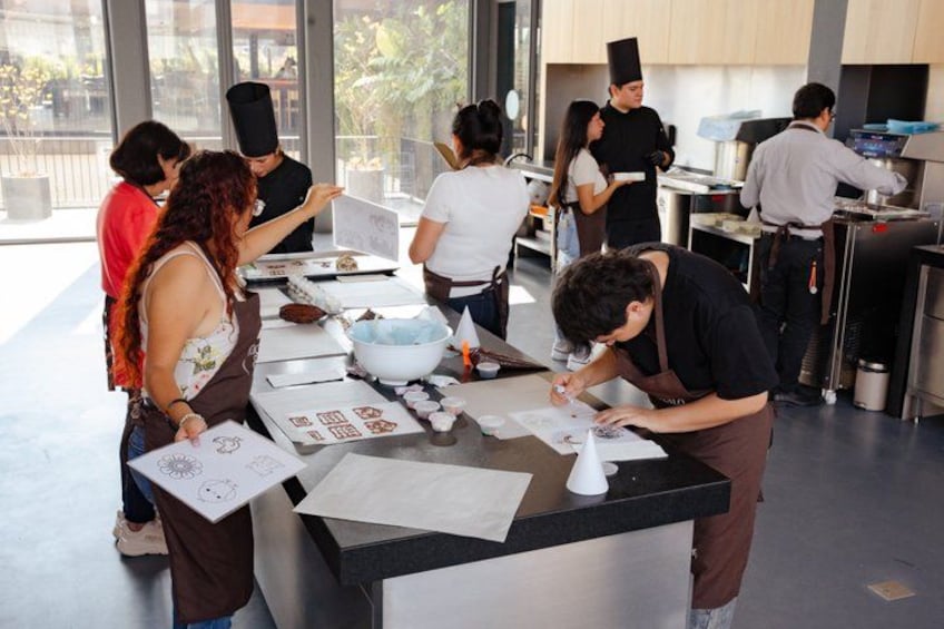 Un grupo de personas participa en una actividad de dibujo en una mesa con material artístico. 4