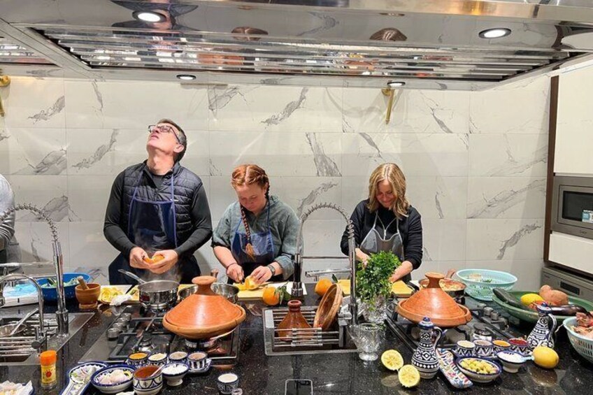 Des chefs préparent des plats dans une cuisine aux murs de marbre, équipée de divers ustensiles de cuisine. 4