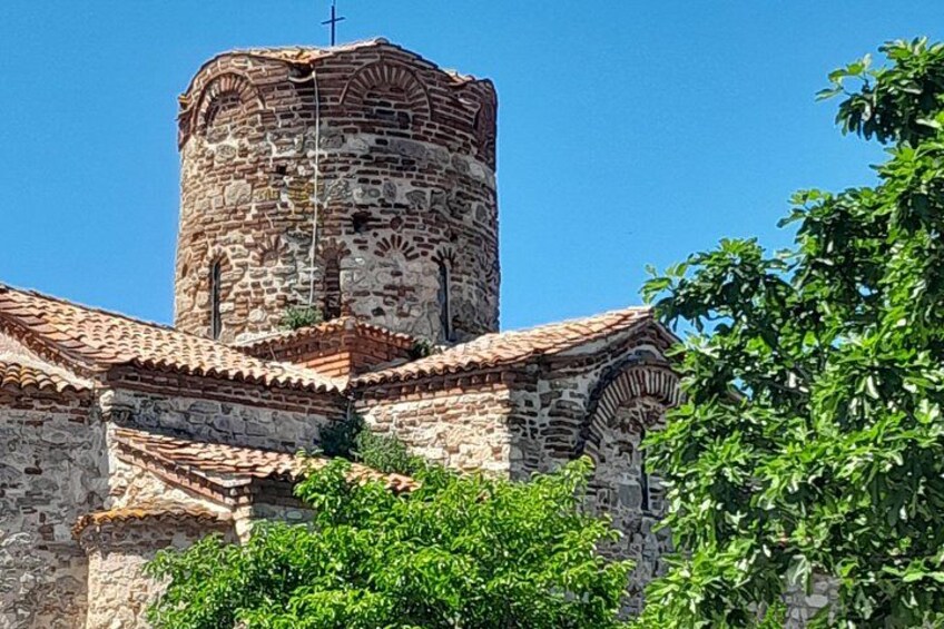 A historic stone church with a bell tower, surrounded by greenery. 2