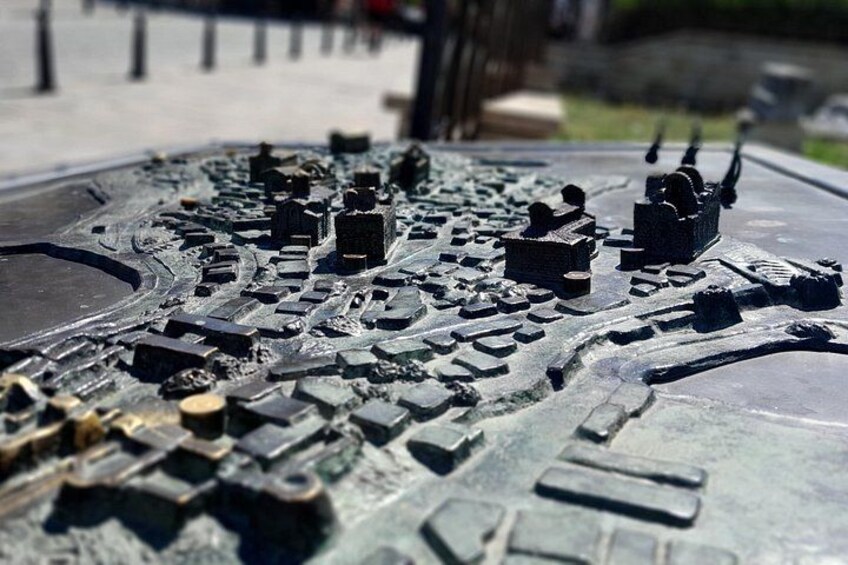 Une sculpture métallique détaillée représentant une vue urbaine, placée sur le capot d’une voiture. 5