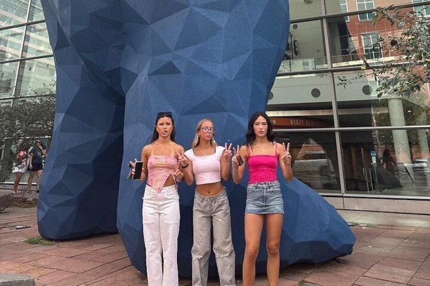 Tre personer poserar framför en stor, blå skulptur. 3